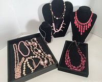 All eight necklaces displayed on and around black forms and trays