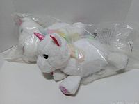 Two adult unicorn plush toys in original plastic packaging