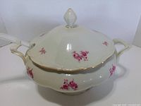Side view of lidded porcelain tureen showing handles, floral pattern, ladle slot