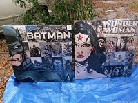 Both Batman and Wonder Woman canvas prints side by side on tarp