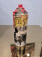 Front view of spray can showing collage graphics, silhouette, symbols and red drips