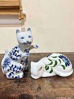 Both ceramic cat figurines, standing and reclining