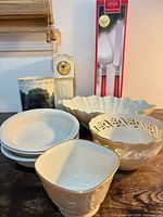 Group shot showing mantle clock, boxed utensil set, mug, stacked plates, square bowl, openwork bowl, scalloped bowl