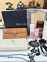 Group shot of wallets, Prada box, gloves, jewelry, cosmetics
