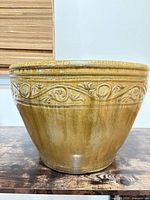 Side view of ceramic planter showing glaze coloration and raised scroll motif