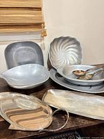 Group of metal bowls, trays and spoons displayed on table