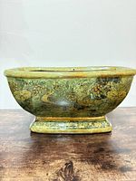 Side view of green pedestal planter displaying bird and floral motif