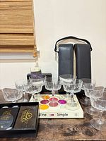 Full lot showing 10 coupe glasses, wine carrier, whiskey stones box and book