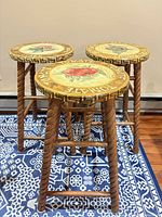 Three wooden bar stools grouped, showing leg style and seat artwork