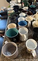 overview of approximately 30 assorted mugs on countertop