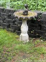 Full view of assembled concrete bird bath showing pedestal, basin and cherub