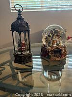 Lantern snow globe and nativity snow globe on glass table