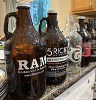 Five growlers lined up on countertop showing front logos