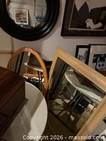 Round black-framed mirror on wall with other mirrors visible