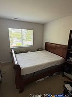 Full room view of wood sleigh bed with mattress