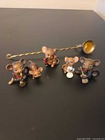 Front view of five mouse figurines and brass ladle