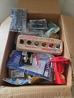 Open box showing egg cartons with coloured golf balls, packaged glove, tees and accessories