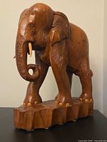 front angled view showing overall form, raised trunk, tusks and carved base