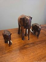 Three wooden elephant figurines on tabletop