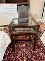 Two square nesting tables, wood frames with glass tops