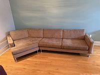 Full view of beige microsuede sectional sofa against wall
