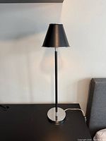 Full view of lamp on table showing stem, shade, base and cord