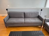Front view of Ethan Allen grey sofa with wood legs on hardwood floor