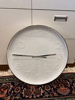 Front view showing entire clock face, raised numerals, silver hands, chrome rim