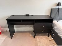 Front angled view of the black Prepac Milo desk showing cubby shelves and drawers