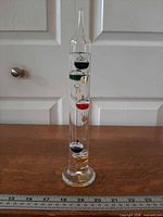 Full view of 10.5 in Galileo thermometer with ruler for scale