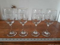 Four matching stemmed goblets in a row with ruler for scale