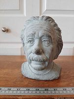 Front view of grey cement Einstein head planter with ruler for scale