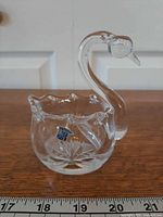 Full view showing swan shape, scalloped rim, star-cut base with ruler for scale