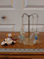Overall lot showing display stand with four hanging clown bell ornaments and separate ceramic clown car figurine