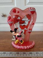 Full view of pink heart-shaped Disney photo frame with Mickey & Minnie figures and heart accents