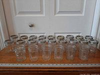 All 24 jars arranged in two rows on table with ruler for scale