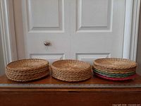 Three stacks of woven wicker plate holders on table with ruler for scale