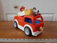 Three-quarter front view of toy fire truck with firefighter figure