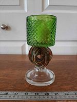 Full view of green glass candleholder with ribbon stem and ruler for scale