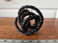 Full view of twisted black glass knot on wood surface