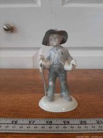 Front view showing entire figurine, boy holding two geese, staff, hat and base