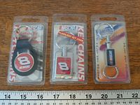 Front view of three packaged NASCAR keychains with ruler for scale