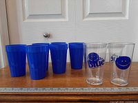 Six blue tumblers and two clear Labatt Blue logo cups lined up