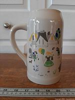 Left side view of white ceramic stein showing Oktoberfest artwork and handle