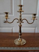 Front view of brass-tone three-arm candelabra showing overall form and finish