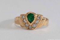 Front view of gold ring showing green center stone and six clear stones