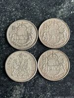 Four Canadian 50-cent coins reverse side showing coat of arms and dates