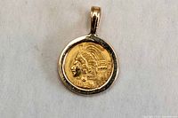Obverse of 22k gold Aztec coin pendant showing warrior profile within bezel and bail