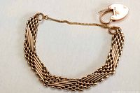 Entire bracelet laid flat showing gate links, padlock clasp and safety chain