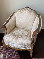 Front angled view of armchair showing carving and upholstery